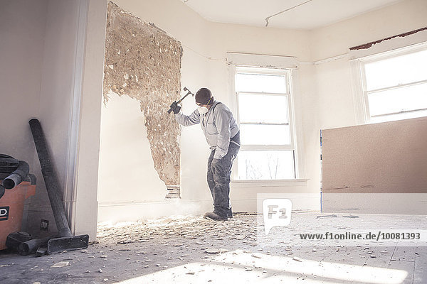 Hispanic construction worker demolishing wall