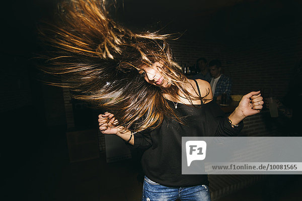 Woman tossing her hair and dancing in nightclub