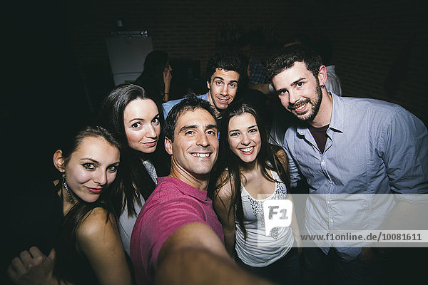 Smiling friends taking selfie in nightclub