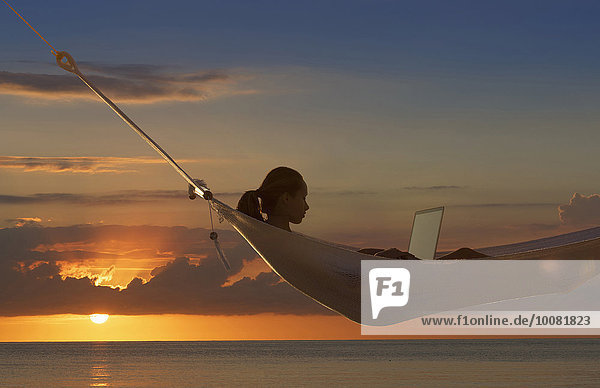 nahe benutzen Europäer Frau Notebook Sonnenuntergang Ozean Hängematte