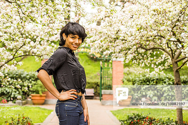Hispanic woman smiling under flowering trees