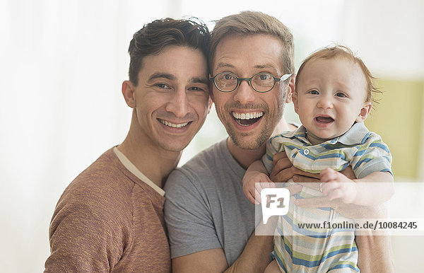 Smiling Caucasian gay fathers holding baby