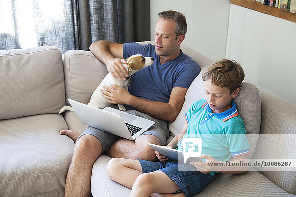 Caucasian father and son using technology on sofa