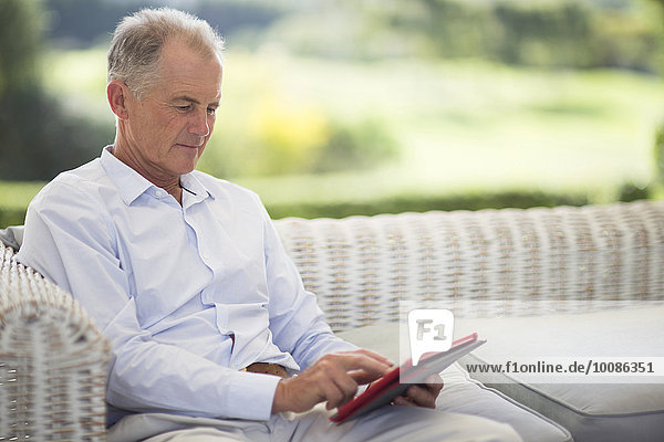 Caucasian man using digital tablet on sofa outdoors