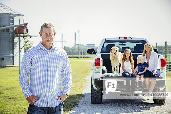 Caucasian man standing near family in truck bed