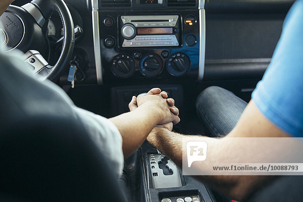 Caucasian couple holding hands in car