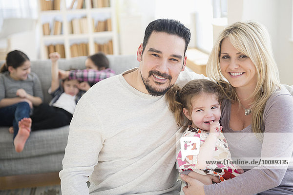 Caucasian parents and daughter smiling in living room