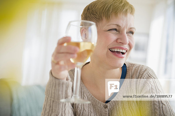 Caucasian woman drinking glass of wine in living room