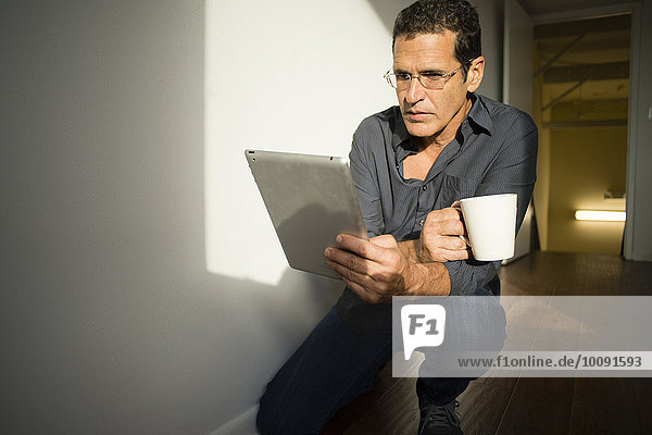 Hispanic businessman using digital tablet in office hallway