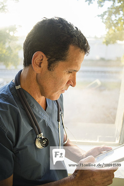 Hispanic doctor using cell phone near window