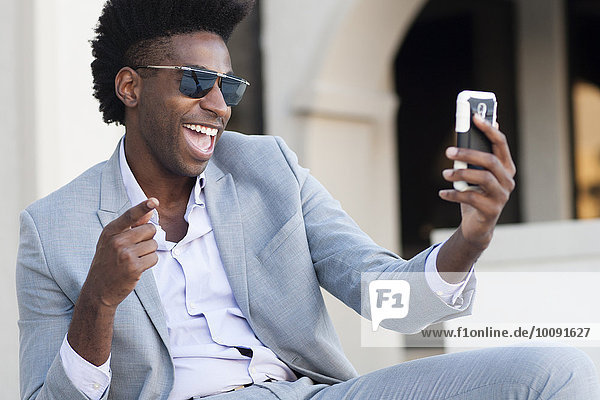 Black businessman taking selfie outside building