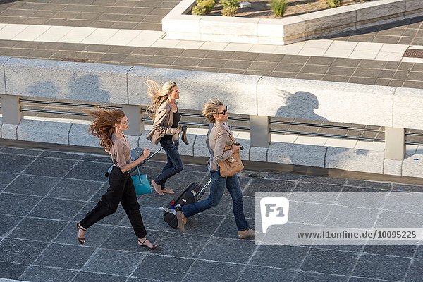 Three adult women running across elevated walkway