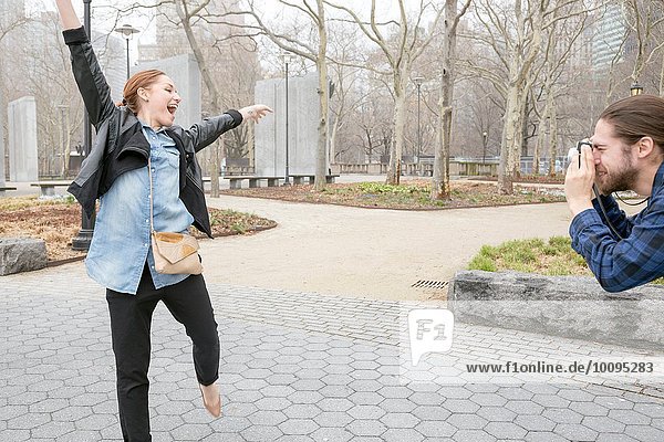 Man taking photograph of girlfriend in park  New York  New York  USA