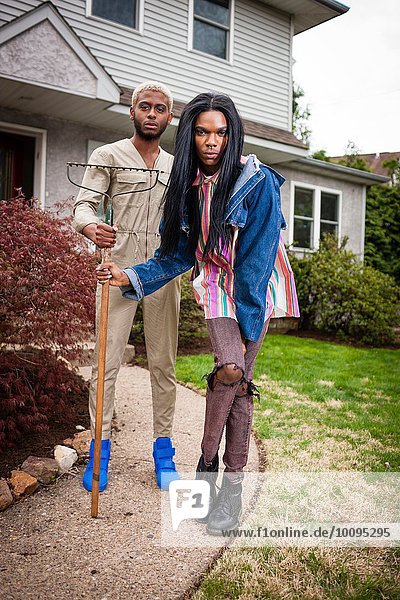 Zwei junge Männer posieren im Vorgarten mit Rechen