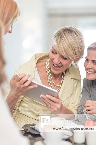 Geschäftsfrau mit digitalem Tablett beim Geschäftsessen