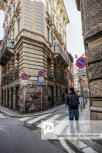 Young man walking through graffiti covered street  Milan  Italy
