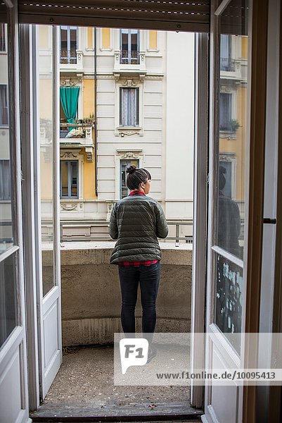Rear view through doorway of woman standing on balcony  Milan  Italy