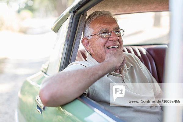 Senior man sitting in back seat of car  smiling