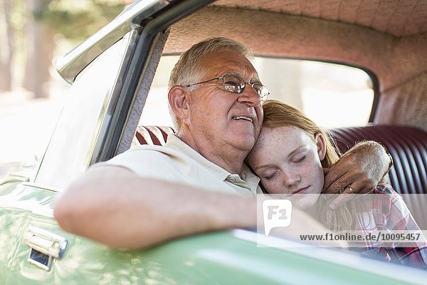 Großvater und Enkelin sitzend auf dem Rücksitz des Autos  Enkelin schlafend