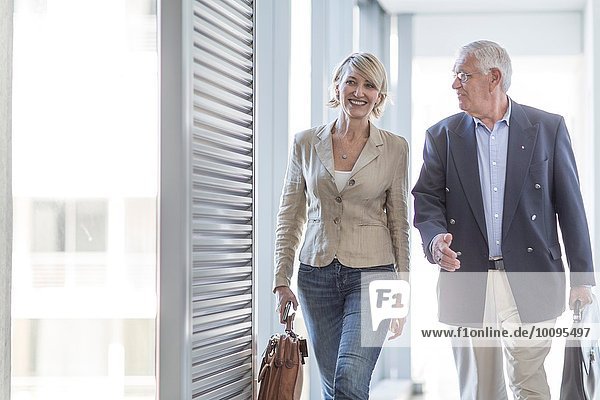 Senior businessman and woman walking in hotel corridor