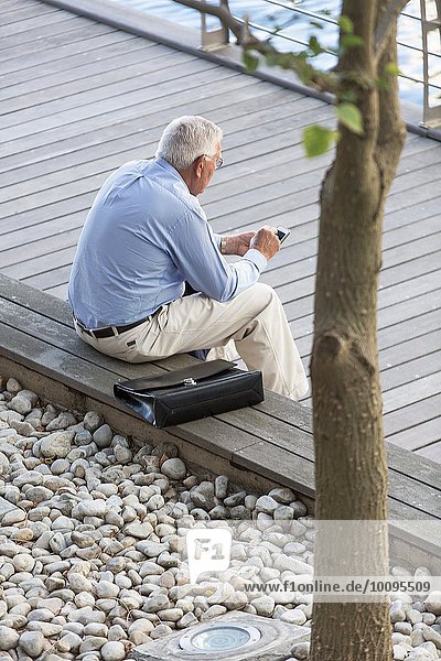 High angle view of senior businessman texting on smartphone on hotel terrace