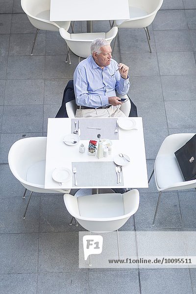High angle view of senior businessman sitting at table on hotel terrace