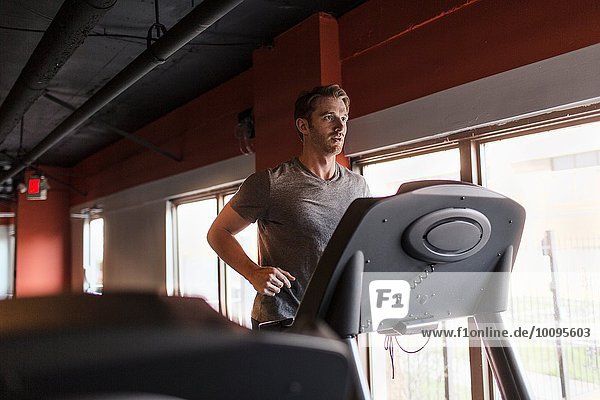 Exhausted mid adult man running on gym treadmill