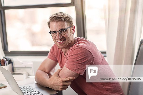 Porträt eines erwachsenen Mannes mit Laptop