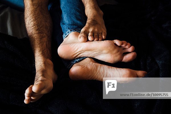 Männliches Paar liegt zusammen und konzentriert sich auf die Füße.
