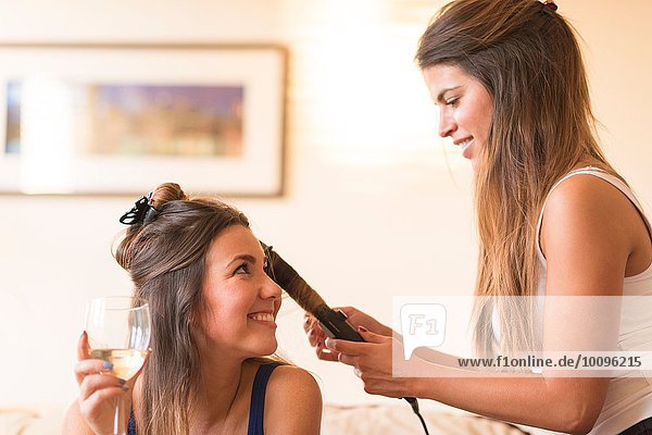 Young woman doing friend's hair