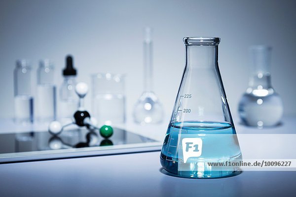 Chemie-Forschung. Erlenmeyerkolben mit farbiger Flüssigkeit und einer digitalen Tablette mit einem Kugel-und-Stift-Molekularmodell auf dem Bildschirm