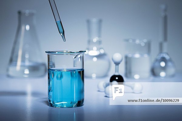 Chemie-Forschung. Pipette zum Überführen von Flüssigkeit in ein Becherglas und ein Kugel-und-Stift-Molekularmodell