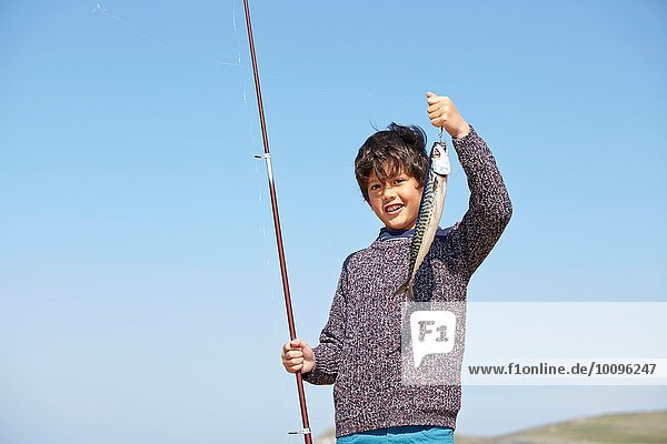 Young boy holding up fishing rod and fish