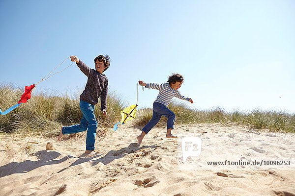 Zwei kleine Jungen  die am Strand Drachen steigen lassen.