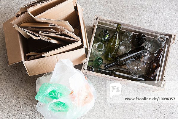 Holzkiste mit leeren Flaschen und Karton für das Recycling