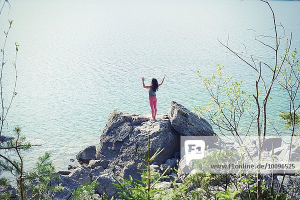 Mittlere erwachsene Frau  stehend auf Felsen am See  in Yogastellung  Rückansicht