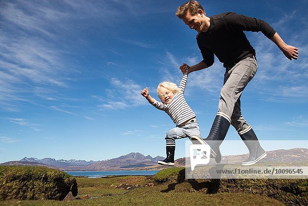 Father and son holding hands running  Isle of Skye  Hebrides  Scotland