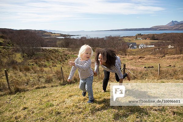 Mother chasing son in field  Isle of Skye  Hebrides  Scotland