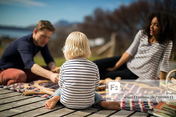 Junge sitzend auf Holzterrasse Rückansicht