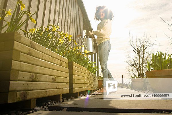Mittlere erwachsene Frau beim Blumen gießen