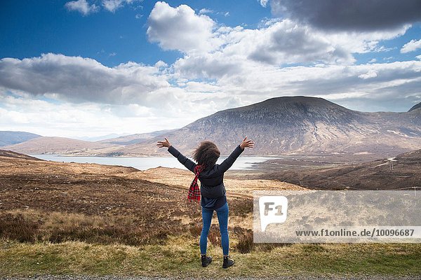 Mittlere erwachsene Frau in den Bergen mit erhobenen Armen  Isle of Skye  Hebrides  Schottland