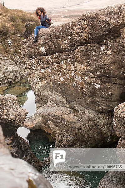 Frau sitzt auf Felsen  Fairy Pools  Isle of Skye  Hebriden  Schottland