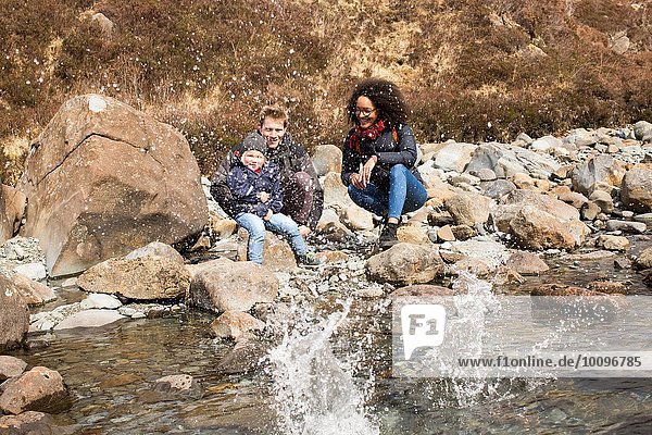 Family throwing stones in pond  Fairy Pools  Isle of Skye  Hebrides  Scotland