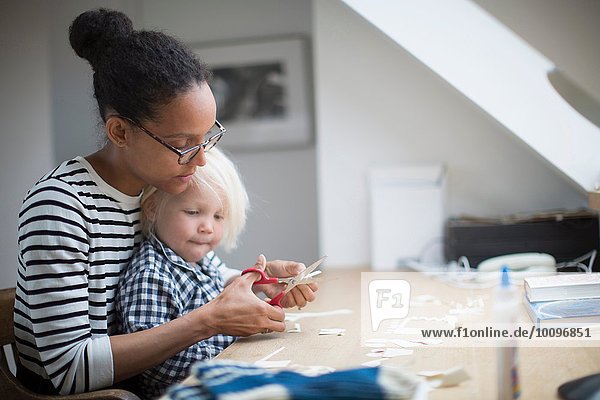 Mutter zeigt dem Sohn wie man eine Schere benutzt.