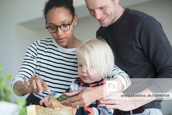 Boy preparing food in kitchen with parents