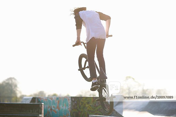 Junger Mann beim Stunt auf bmx im Skatepark  Rückansicht