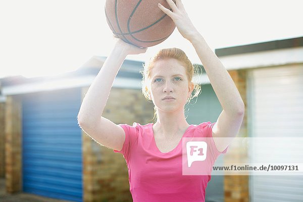 Portrait of woman holding basketball above head