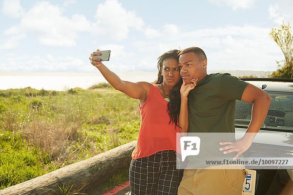 Junges Paar mit Smartphone  nimmt Selfie  macht Gesichter