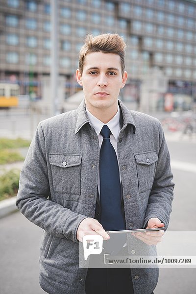 Portrait of young businessman commuter holding digital tablet.
