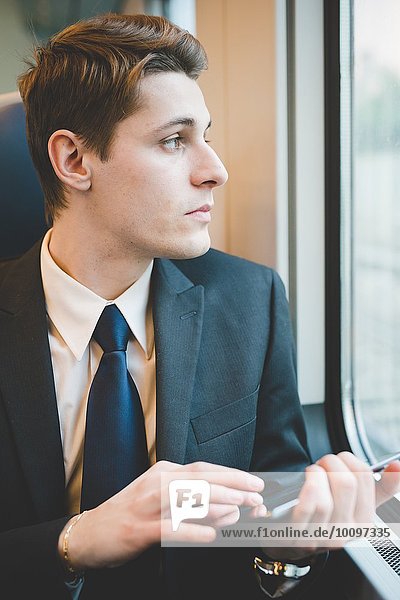 Portrait of young businessman commuter using digital tablet on train.